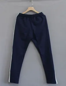 Close-up of navy blue men's slim fit athletic joggers featuring white side stripes.