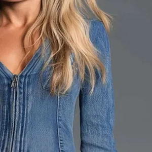 Close-up detail of blue denim mini dress with front zipper and pleated texture