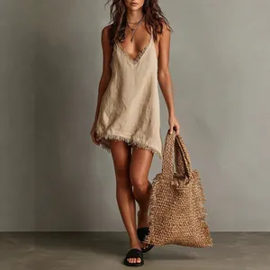 Bohemian style beige linen mini dress with fringe detailing and oversized woven tote bag