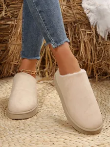 Detail view of beige suede snow boots with soft faux fur lining on a rustic woven mat.