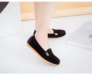 Close-up of black suede loafers featuring an elegant gold metal buckle and rubber sole