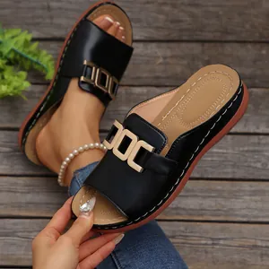 Detailed macro view of black casual slip-on sandals with decorative gold chain buckle