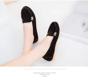 Detailed view of comfortable black suede loafers with elegant gold buckle on a model
