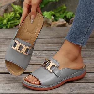 Close-up of grey women's slide sandals with elegant gold metal buckle detail.