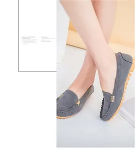 Detailed view of grey suede women's loafers with metal buckle detail on model's feet