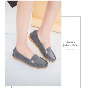 Classic grey suede flat loafers featuring a metal buckle on model's feet in studio.
