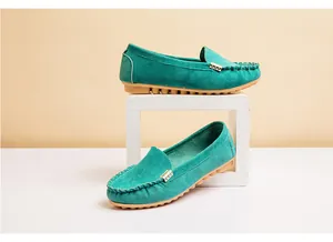 Detailed view of teal suede loafers featuring a gold metal buckle and round toe.