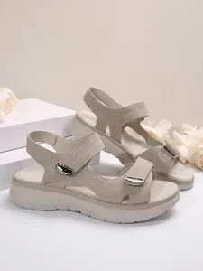 Detail van beige wedge sandalen met klittenbandsluiting en zilveren gesp-accenten.