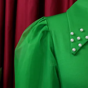 Detail of green dress with puff mesh sleeves and faux pearl collar embellishments.