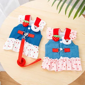 Detailed view of two denim pet harness dresses with strawberry and bear accents
