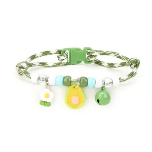 Detailed view of the cute avocado and bell charms on a green braided pet necklace