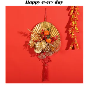 Detail view of a festive golden fan wreath with red berries for Chinese New Year.