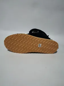 Detailed bottom view of black fringe winter boots featuring a wavy gum anti-slip sole