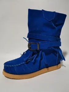 Detailed view of the bright blue suede tassel boots with ornate metal buckle and flat sole