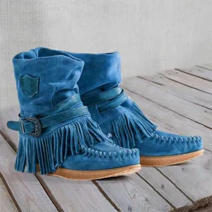Macro detail of bohemian blue suede boots featuring vintage fringe and a metallic buckle design.