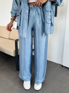 Detail view of light blue textured satin wide-leg pants featuring a drawstring waist