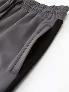 Close-up detail of grey sports pants featuring elastic waistband and black side stripe.