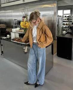 Modische braune Wildlederjacke für Damen kombiniert mit weit geschnittener Jeanshose.