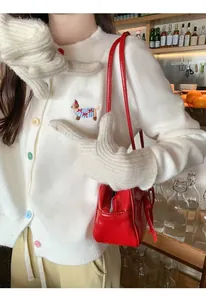 Detailed view of white cardigan featuring colored buttons and cute dog embroidery