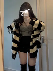 Close-up detail of a loose black and white striped knit cardigan on a female model