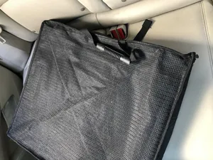 Détail d'un tapis de siège de voiture pour animal noir pliable sur un siège en cuir.