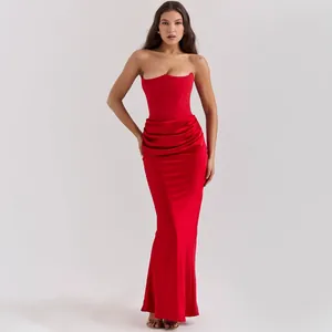Full-length view of a red strapless evening dress highlighting corset top and draped waist