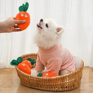 Small white dog playing with cute plush carrot toys inside a natural wicker basket.