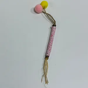Natural silvervine molar stick for cats featuring colorful pom-poms and raffia grass detail