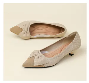 Détail de chaussures à talons chaton en maille beige avec bout pointu et un nœud.