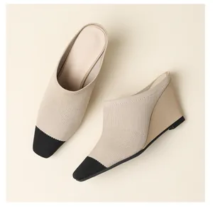 Vue détaillée de mules à semelle compensée en tricot beige avec un bout noir contrasté.