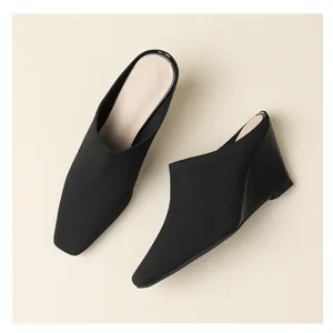Vue détaillée de dessus de mules compensées noires en maille pour femmes sur beige