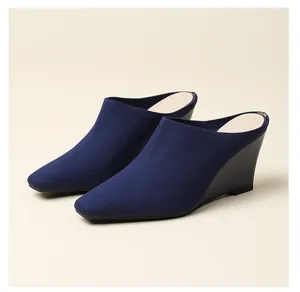 Vue détaillée du tissu tricoté bleu marine sur ces chaussures mules à talon compensé.