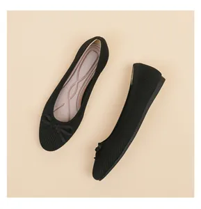 Close-up of black knitted ballet flats with elegant bow detail on beige background