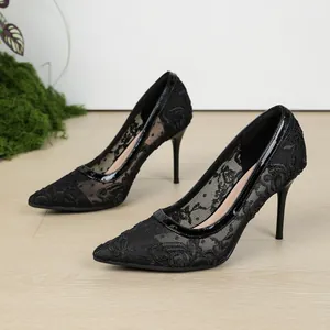 Primer plano de tacones de aguja con bordado de encaje negro y ribete de charol