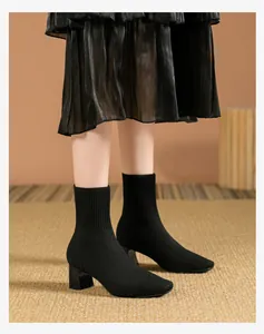 Primer plano de botines de calcetín de punto negro con tacón de bloque y punta cuadrada elegante