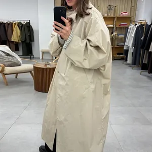 Mirror selfie of woman wearing a loose light apricot double-breasted trench coat