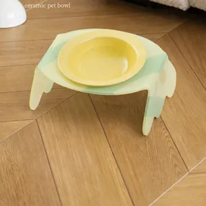 Detailed side view of yellow ceramic pet bowl on a tilted light green acrylic stand