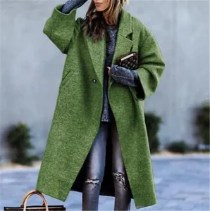 Detail of a long green wool coat with notched lapels on a model in a city setting