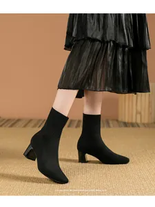 Vista de detalle de botines de punto negros con tacón grueso y diseño de punta cuadrada.