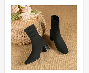 Primer plano de botines de calcetín de punto negro con tacón grueso y punta cuadrada.