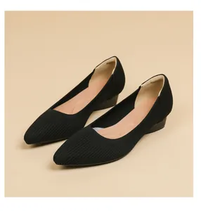 Primo piano di scarpe in maglia nera a punta con trama a righe traspirante.