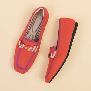 Λεπτομερής κάτοψη πορτοκαλί πλεκτών loafers με κομψά διακοσμητικά μαργαριταρένια στοιχεία