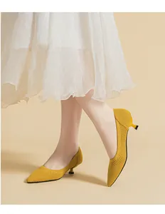 Close-up detail view of stylish yellow fly-knit pointed-toe kitten heel pumps on model