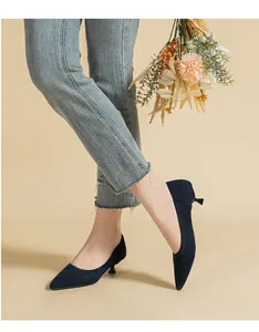 Macro view of navy blue breathable knit pointed-toe kitten heel pumps on a model.