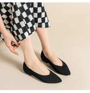 Model draagt zwarte puntige gebreide ballerina's met een stijlvolle geblokte rok aan