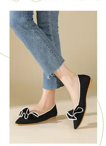Nahaufnahme von schwarzen flachen Mesh-Schuhen mit eleganter Rüschenschleife.