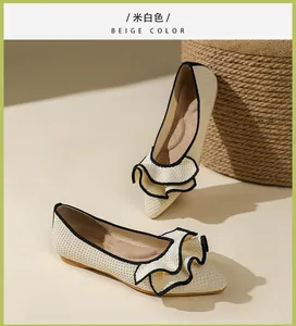 Nahaufnahme von beigen spitzen Ballerinas mit Rüschen und schwarzem Rand.
