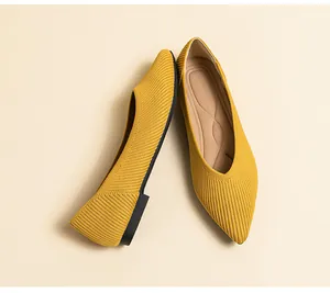 Detailopname van stijlvolle gele gebreide spitse ballerina's met zachte streeptextuur