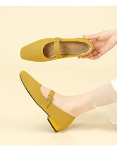 Detail view of breathable yellow fly-knit Mary Jane shoe with buckle strap texture.