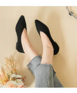 Close-up view of black pointed toe knit flat shoes worn by a model in denim jeans
